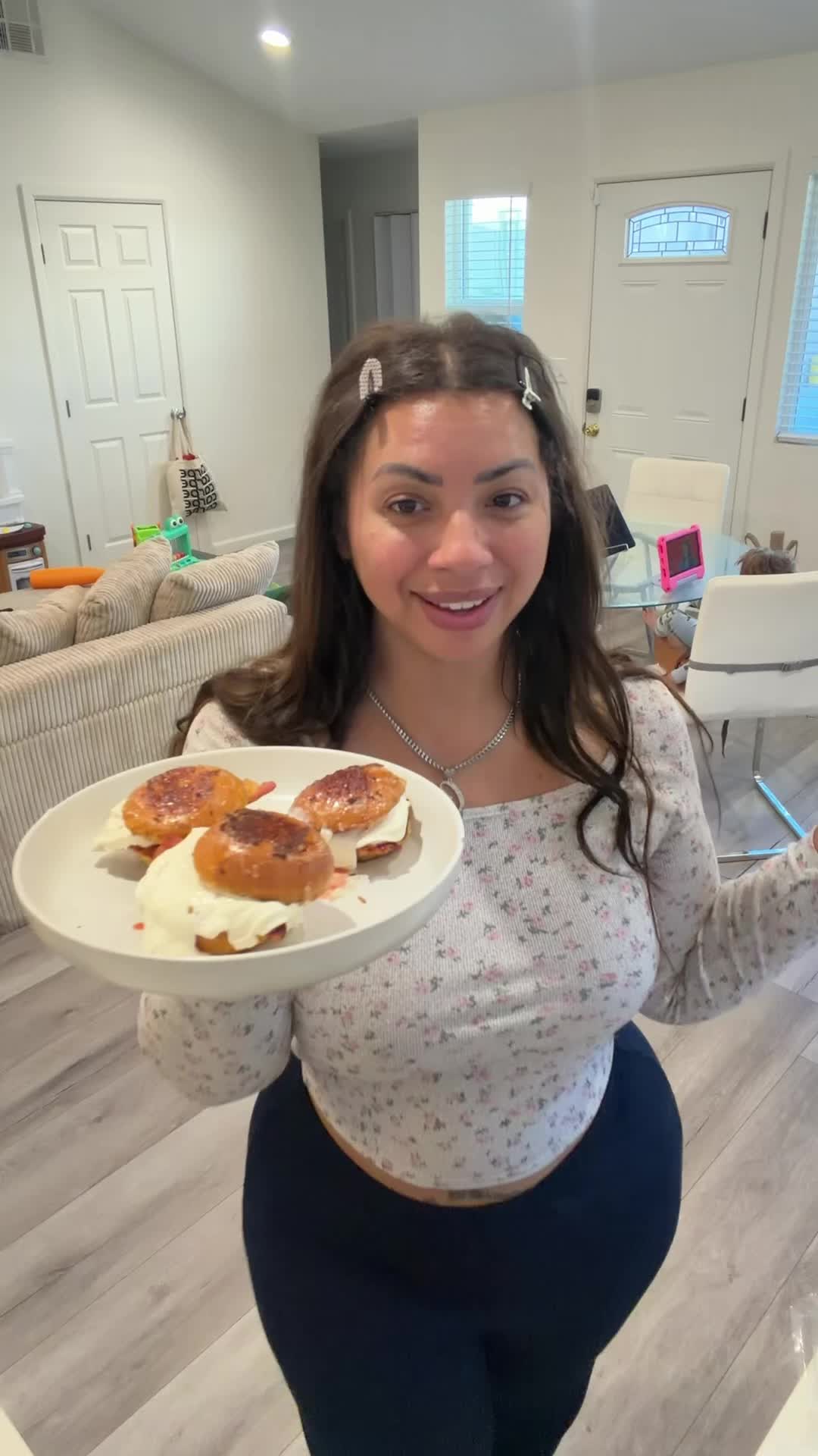 Ciara holding brioche French toast buns with bacon, strawberry jam, and maple whipped cream