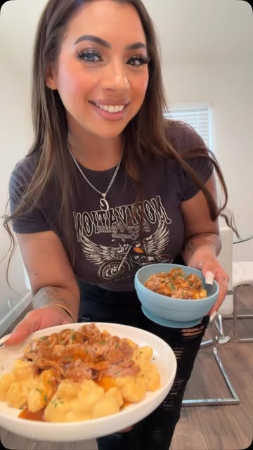 Ciara holding a plate of gnocchi with pulled meat and gravy